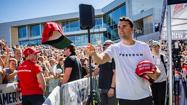 a man holding a hat and standing in front of a crowd